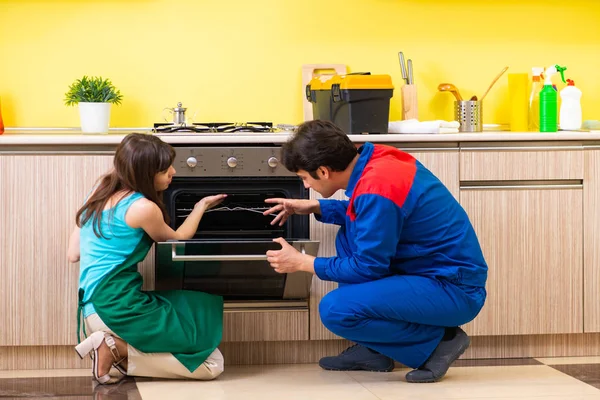 Frau diskutiert mit Bauunternehmer in Küche über Reparatur — Stockfoto