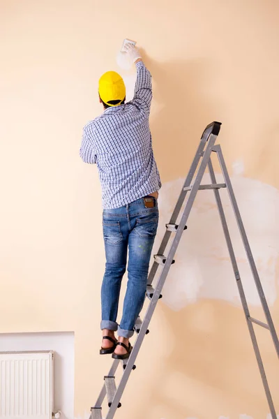 Jungunternehmer schleift Wand mit Schleifpapier ab — Stockfoto