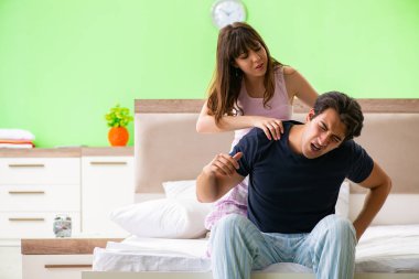 Yatak odasında kocasına masaj yapan bir kadın. 