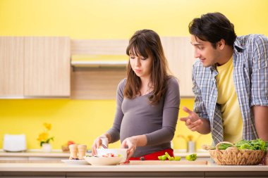 Erkek ve hamile kadın mutfakta salata hazırlıyorlar. 