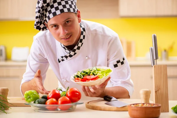 Joven cocinero profesional preparando ensalada en la cocina — Foto de Stock