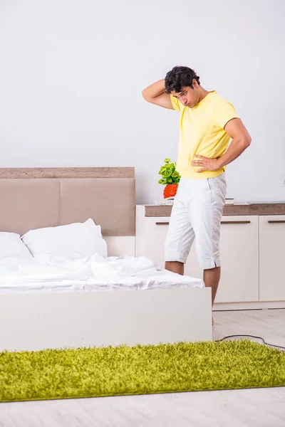 Jonge knappe man schoonmaken in de slaapkamer — Stockfoto