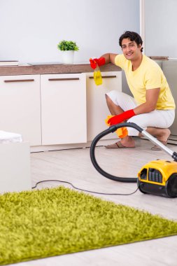 Genç yakışıklı adam yatak odasını temizliyor.