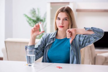 Kadın acıyla baş etmek için hap alıyor.