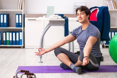 Ofiste egzersiz yapan genç bir erkek.