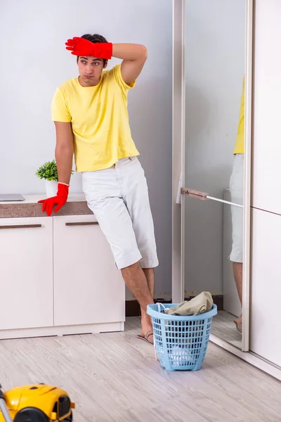 Jonge knappe man schoonmaken in de slaapkamer — Stockfoto