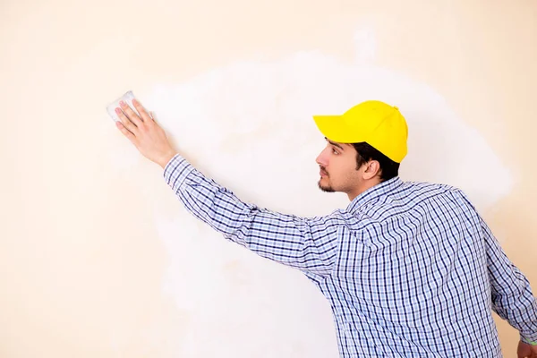 Contratista joven lijando pared con papel de lija — Foto de Stock