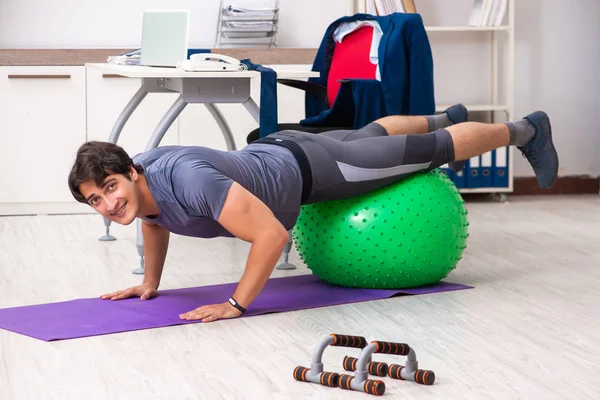 Young male employee exercising in the office — Stock Photo, Image