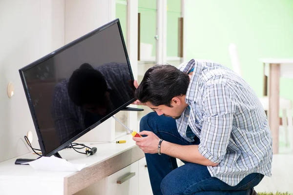 Jovem marido reparar tv em casa — Fotografia de Stock