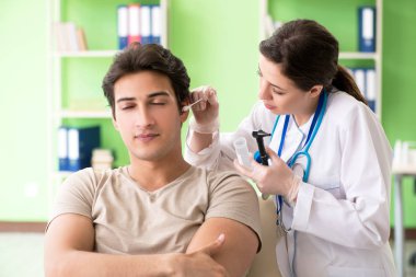 Tıbbi muayene sırasında kadın doktor hastaların kulaklarını kontrol ediyor. 