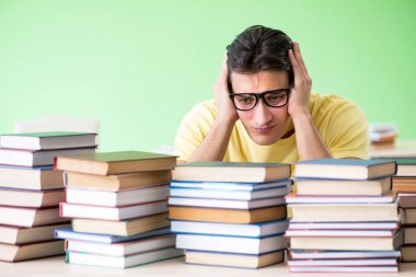 Sınavdan önce okumak için çok fazla kitabı olan öğrenci