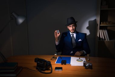 Dedektif karanlık odada klasik bir konseptle oturuyor.