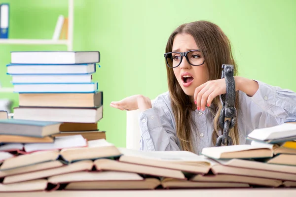 Mladá studentka připoutaná řetězy ke stolu a připravující se na zkoušky — Stock fotografie