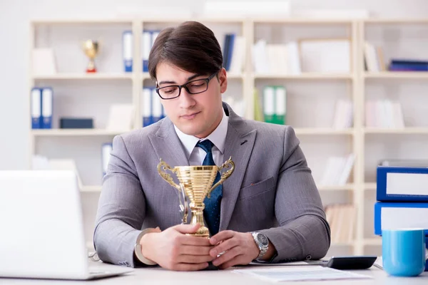 Бизнесмен с золотой чашкой в офисе — стоковое фото