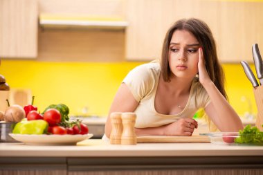 Genç bayan mutfakta salata hazırlıyor.