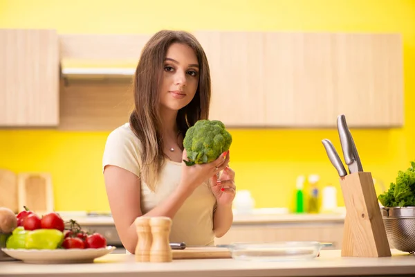 Jovem mulher preparando salada em casa na cozinha — Fotografia de Stock