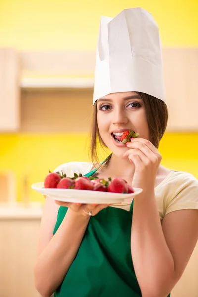 Jovem cozinheira comendo morangos — Fotografia de Stock