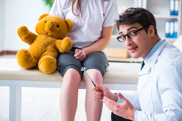 Doctor checking up young girls reflexes with hammer — Stock Photo, Image