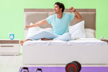 Pijamalı genç adam sabah egzersizi yapıyor. 