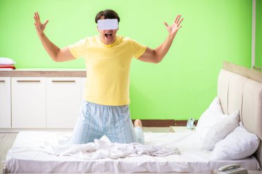 Yatak odasında sanal gözlüklü genç adam. 