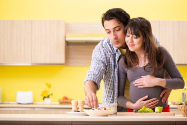 Erkek ve hamile kadın mutfakta salata hazırlıyorlar. 