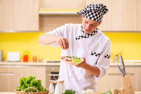 Joven cocinero profesional preparando ensalada en la cocina — Foto de Stock