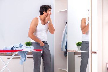 Genç adam yatak odasında ütü yapıyor. 