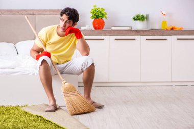 Genç yakışıklı adam yatak odasını temizliyor.