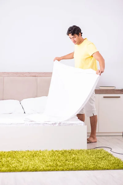 Genç yakışıklı adam yatak odasını temizliyor. — Stok fotoğraf