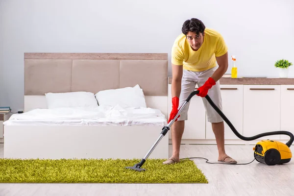 Joven hombre guapo limpieza en el dormitorio — Foto de Stock