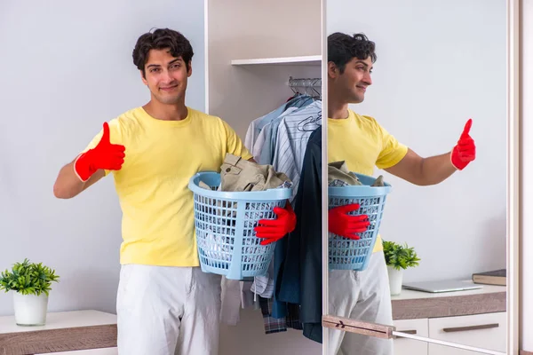 Jonge knappe man schoonmaken in de slaapkamer — Stockfoto