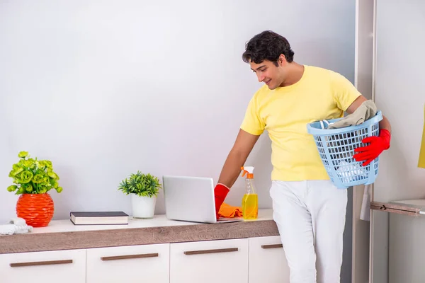 Jonge knappe man schoonmaken in de slaapkamer — Stockfoto