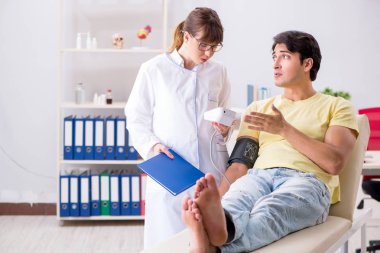 Genç doktor hastaların tansiyonunu ölçüyor.