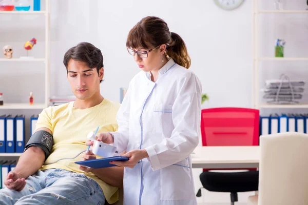 Giovane medico che controlla la pressione sanguigna dei pazienti — Foto Stock