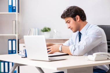 Genç yakışıklı işadamı ofiste çalışıyor.