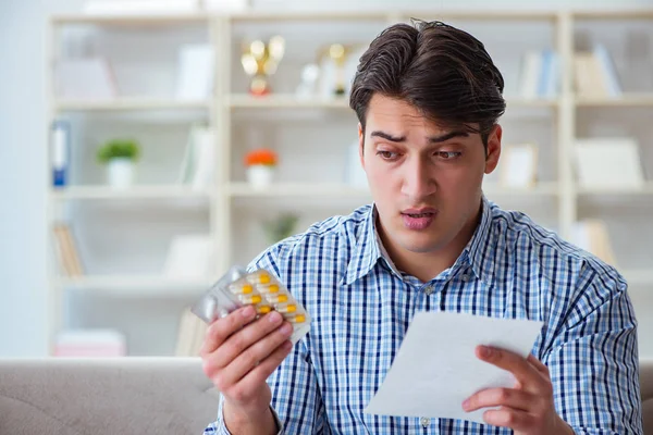 Young man sitting on the sofa with pills and prescription — Stock Photo, Image