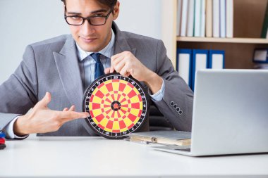 Ofiste oturan dart tahtası olan bir iş adamı.