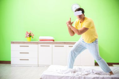 Yatak odasında sanal gözlüklü genç adam. 