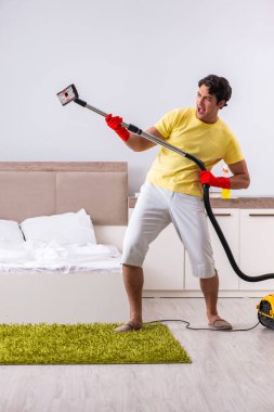 Genç yakışıklı adam yatak odasını temizliyor.