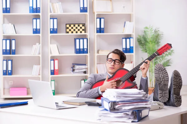 Mladý pohledný podnikatel hrající na kytaru v kanceláři — Stock fotografie