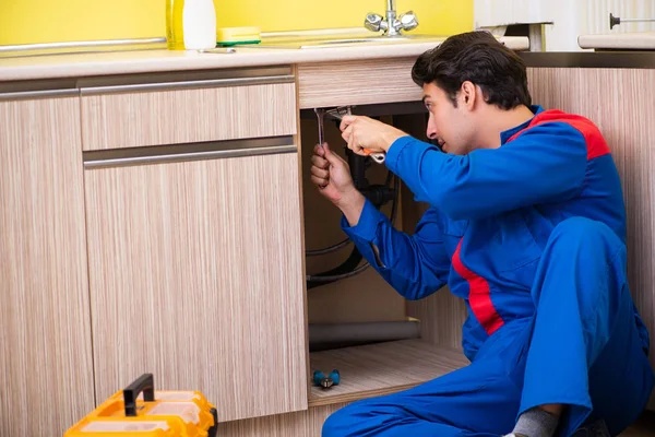 Fontanero reparación lavabo en la cocina — Foto de Stock