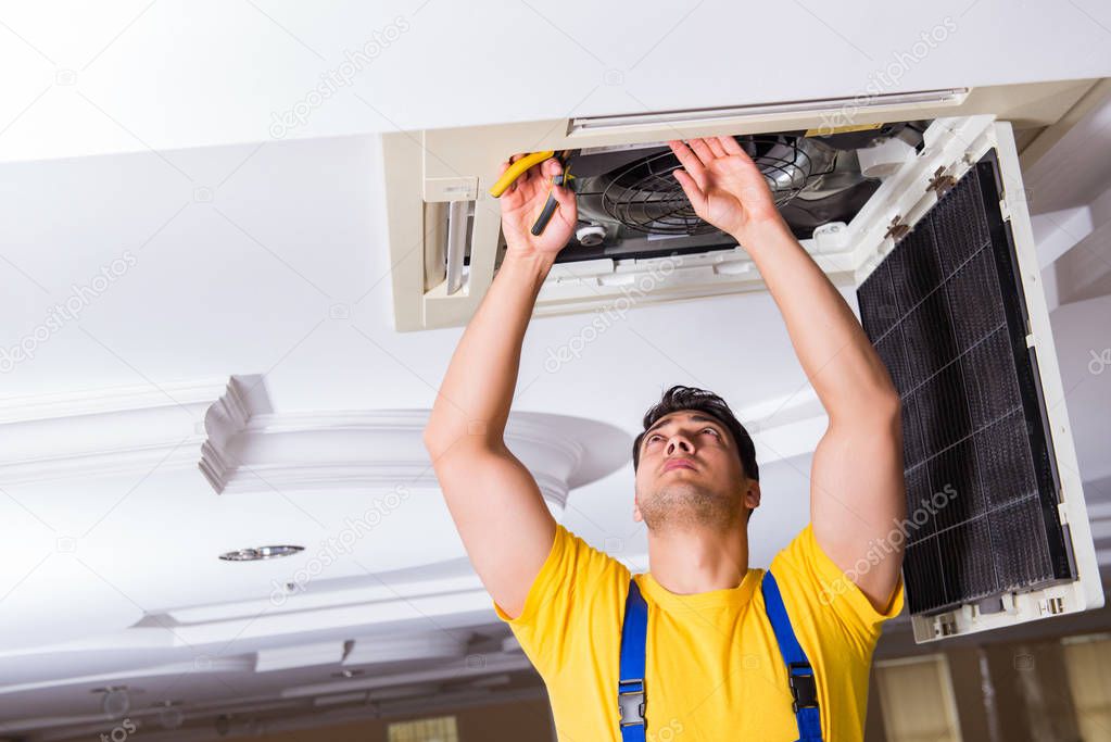 Repairman repairing ceiling air conditioning unit