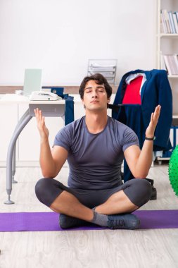 Ofiste egzersiz yapan genç bir erkek.