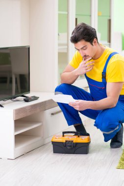 Erkek profesyonel tamirci evde televizyon tamir ediyor.
