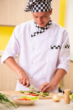 Genç profesyonel aşçı mutfakta salata hazırlıyor.