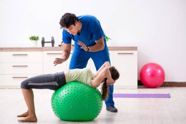 Spor hocası egzersiz sırasında sporcuya yardım ediyor.