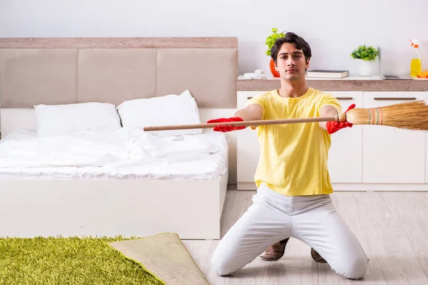 Jonge knappe man schoonmaken in de slaapkamer — Stockfoto