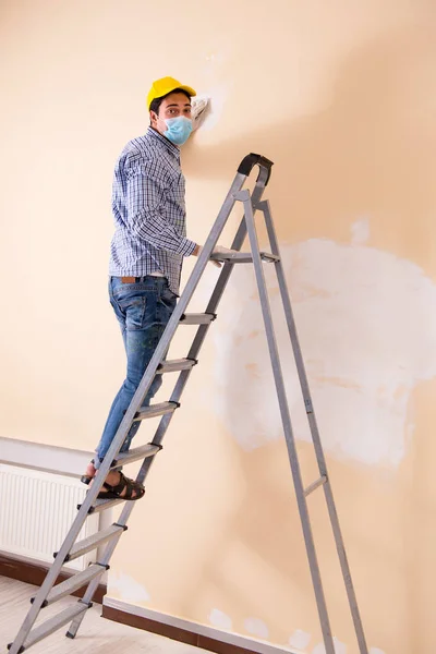 Contratista joven lijando pared con papel de lija —  Fotos de Stock