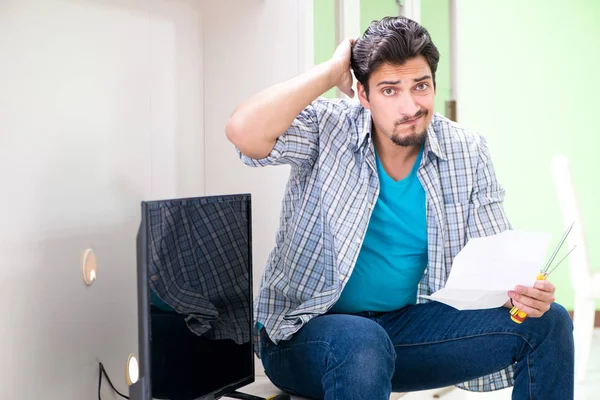 Young man husband repairing tv at home