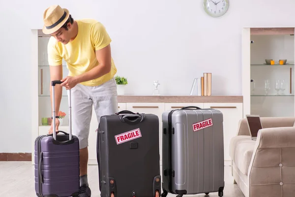 Чоловік збирається у відпустку з крихкими валізами — стокове фото
